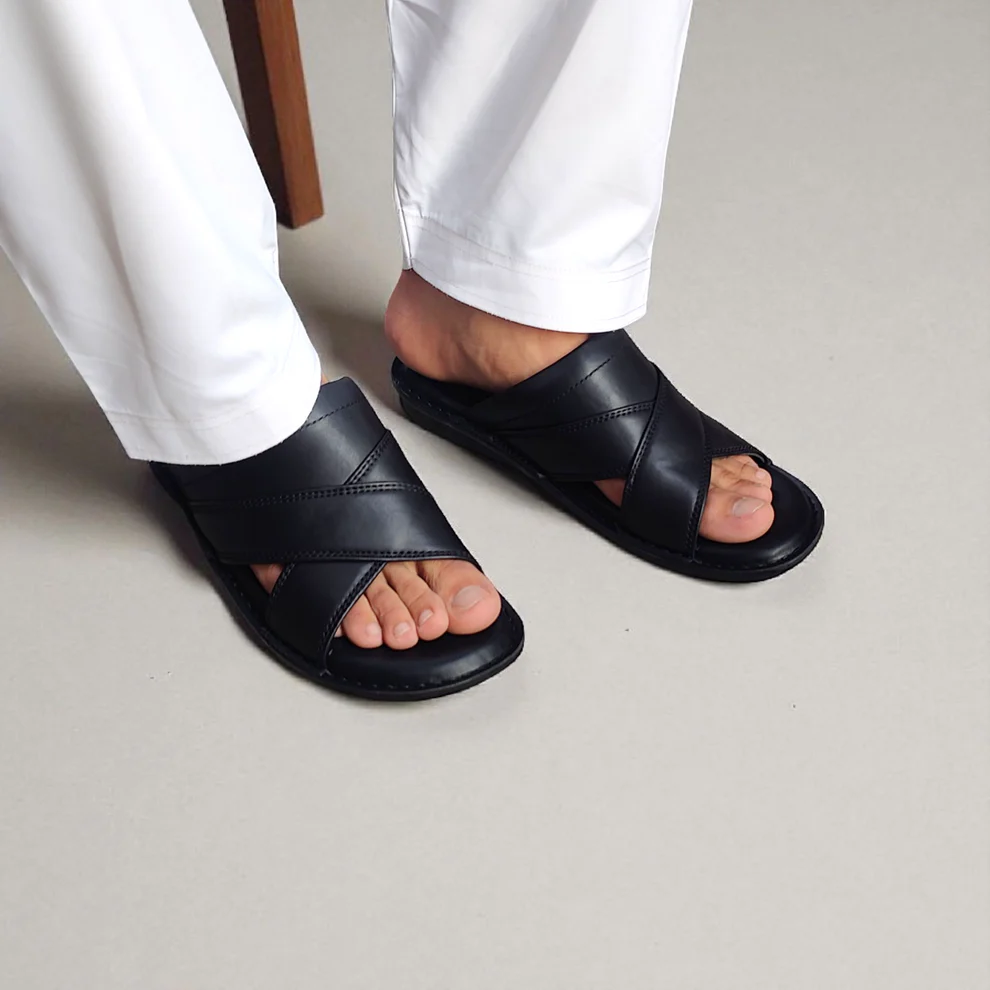 Sandales homme noires portées avec pantalon blanc